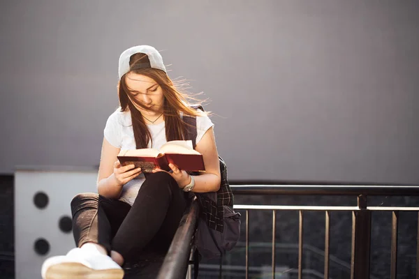 Söt flicka sitta på trappan och läsa bok med hörlurar — Stockfoto