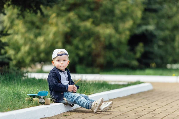 Mały chłopiec siedzą w zielony rozmycie tła — Zdjęcie stockowe