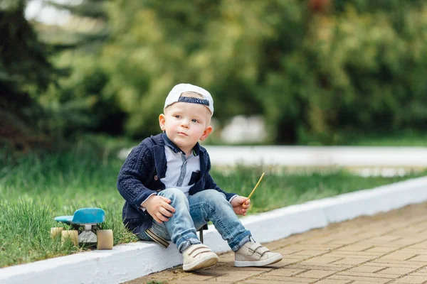 緑ぼかし背景に小さな男の子が座っています。 — ストック写真