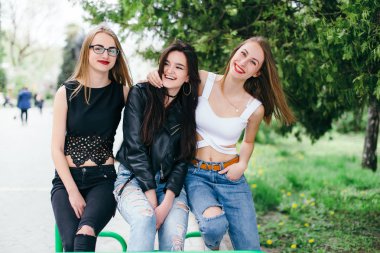 Üç kız park ile bankta oturmak