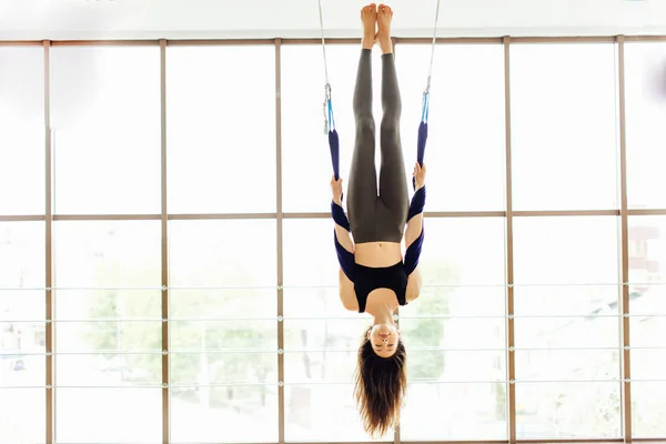 Chica joven hacer volar yoga y se extiende sobre fondo blanco — Foto de Stock