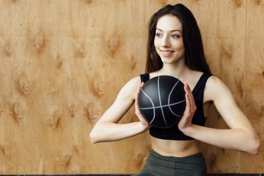 Genç kız woth top ahşap arka plan duvar üzerinde egzersiz