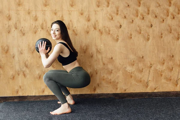 Giovane ragazza fare esercizio woth palla su legno sfondo parete — Foto Stock