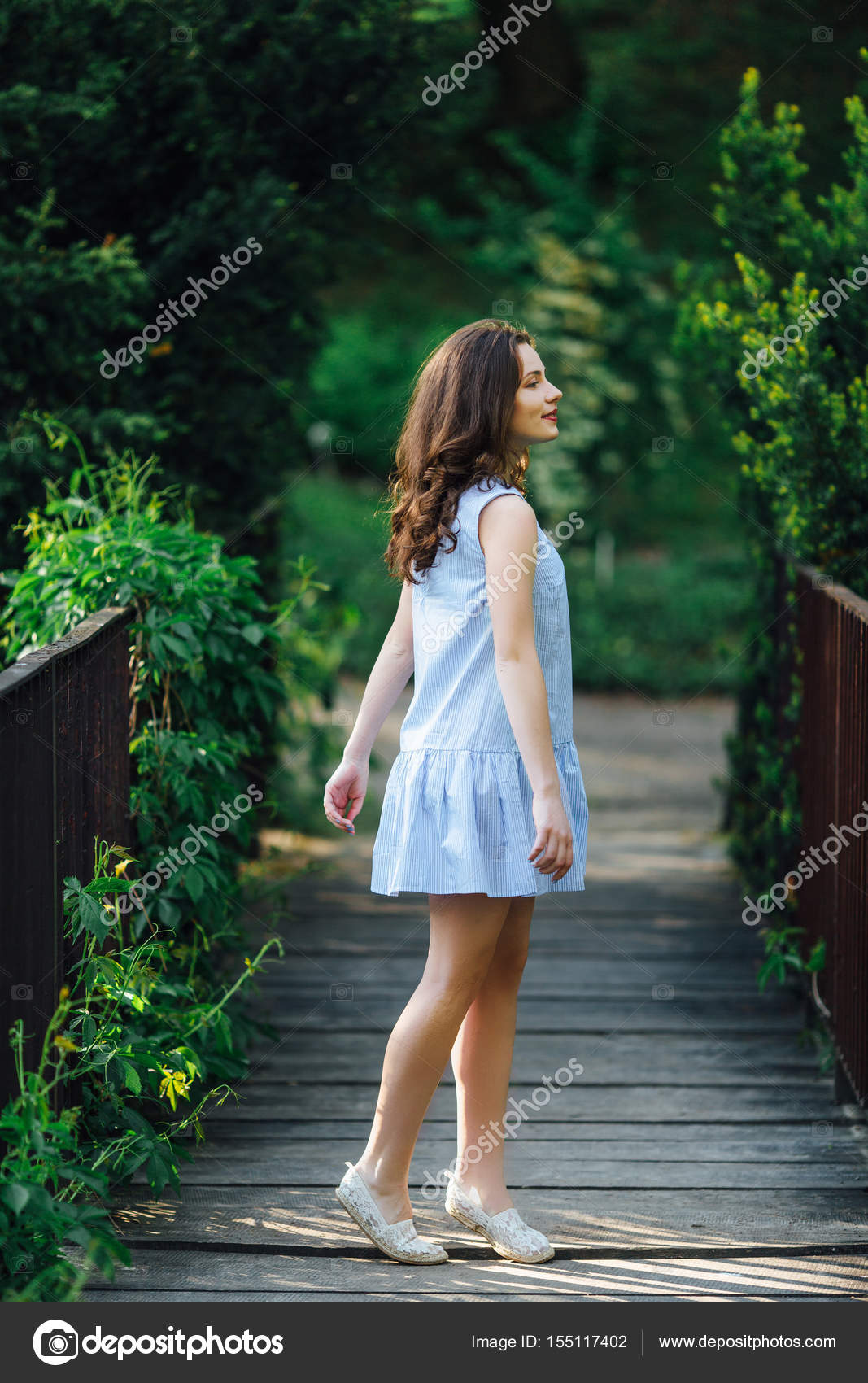 Girl pose to camera at park background with her dress Stock Photo by