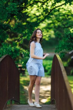 Kız elbisesi ile park arka plan, kamera için poz