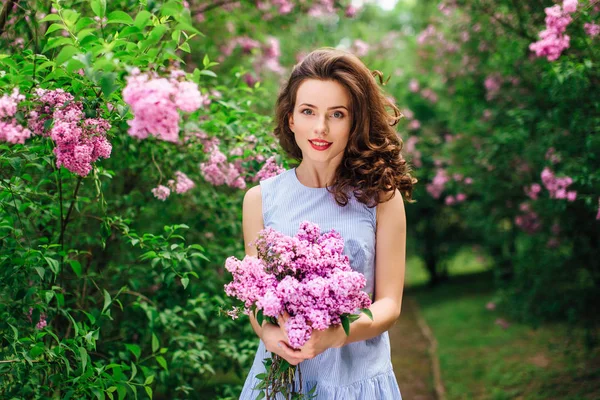 Jeune fille debout au fond du parc avec bouquet de fleurs — Photo