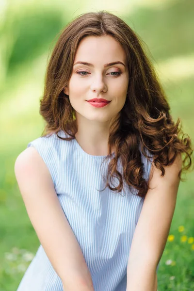 Jeune fille debout au fond du parc avec bouquet de fleurs — Photo