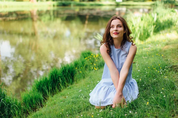 Jeune fille debout au fond du parc avec bouquet de fleurs — Photo