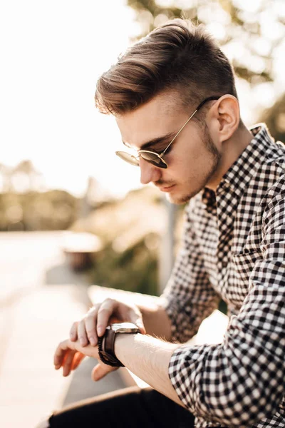 Модний чоловік дивиться на годинник з білим фоном вулиці — стокове фото