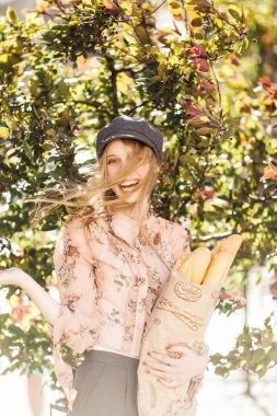 Genç model sokakta stand ve ekmek tutun 