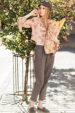 Genç model sokakta stand ve ekmek tutun 