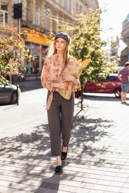 Genç model sokakta stand ve ekmek tutun 