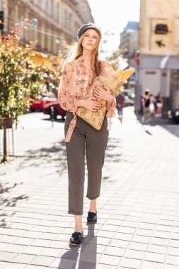 Genç model sokakta stand ve ekmek tutun 