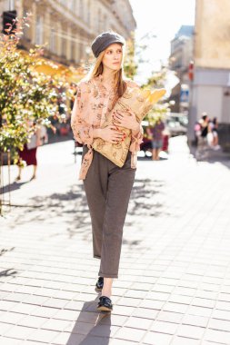 Genç model sokakta stand ve ekmek tutun 