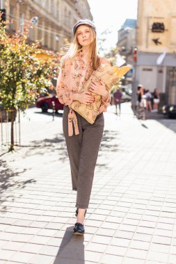 Genç model sokakta stand ve ekmek tutun 