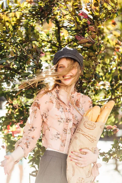 Genç model sokakta stand ve ekmek tutun 