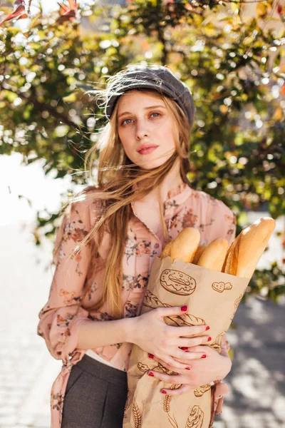 Genç model sokakta stand ve ekmek tutun 