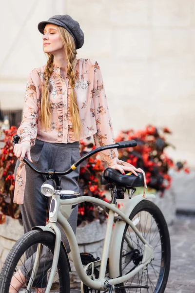 Молодая модель стоит на улице и держит хлеб с велосипедом — стоковое фото