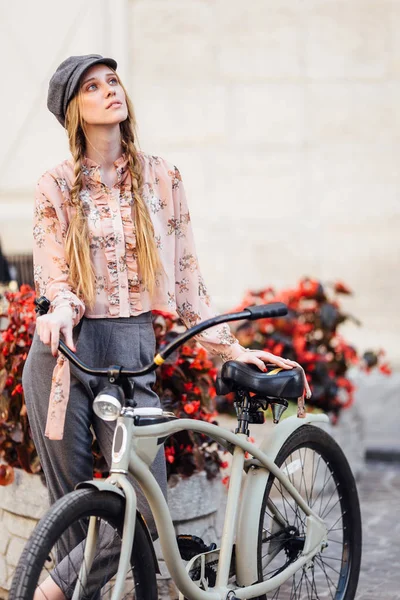 Молодая модель стоит на улице и держит хлеб с велосипедом — стоковое фото