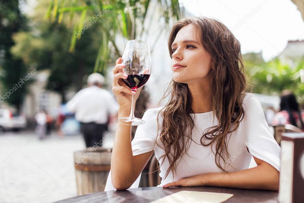 Girl drink glass of wine at the table of restourant