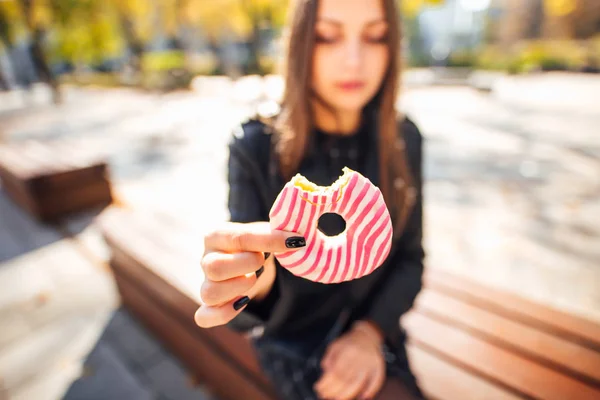 若い女の子は、公園秋バック グラウンドでドーナツを食べる — ストック写真