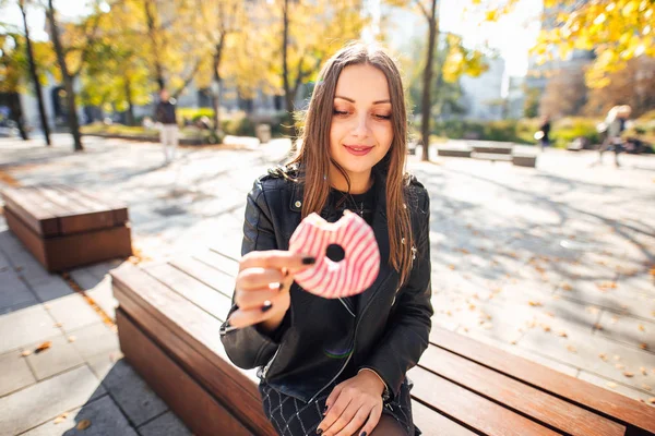 Jong meisje donut eten in park herfst achtergrond — Stockfoto