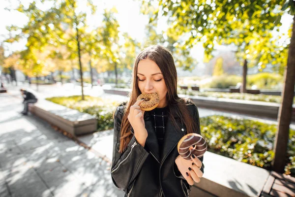 若い女の子は、公園秋バック グラウンドでドーナツを食べる — ストック写真