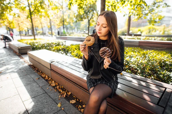 Jeune fille manger beignet dans le parc automne fond — Photo