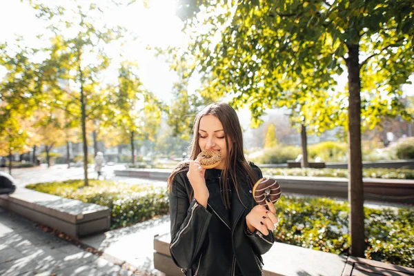 어린 소녀 공원이을 배경에서 도넛을 먹을 — 스톡 사진
