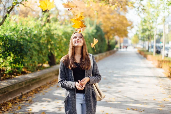 Jeune femme jette des feuilles dans la rue — Photo