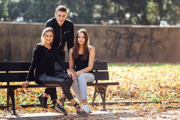 Trois amis s'assoient sur le parc et parlent — Photo