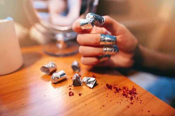 Closeup shot of a woman using a foil to give a nail manicure.