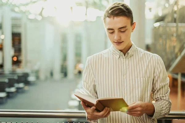 Homem stsnd na biblioteca e ler livro com borrão de fundo sol — Fotografia de Stock