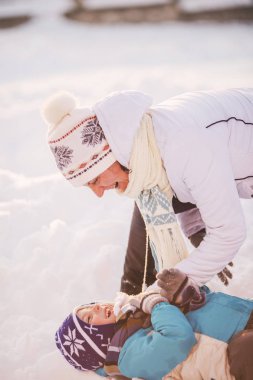 Eğleniyor, kış oynarken mutlu aile anne ve çocuk güneş 