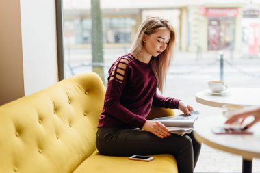 Genç kız oturup fincan kahve ve kamera için bir gülümseme ile