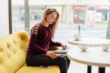 Genç kız oturup fincan kahve ve kamera için bir gülümseme ile