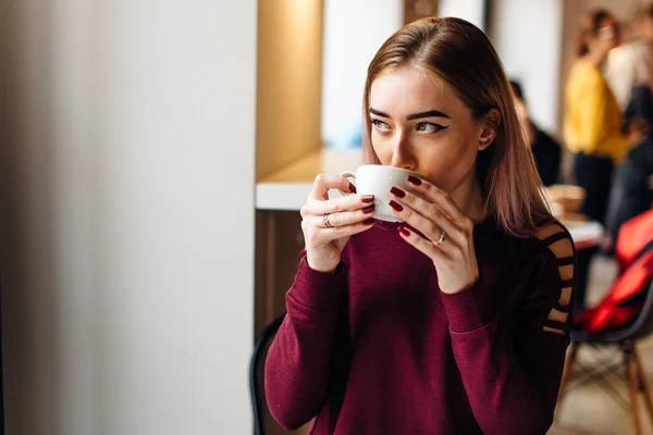 Jong meisje zitten met een kopje koffie en een glimlach op de camera — Stockfoto