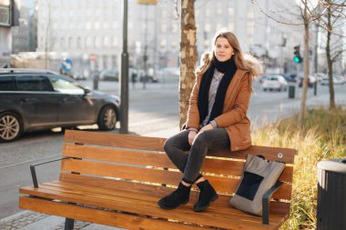 Genç güzel kız bankta oturup. Bir elinde onun eşarp asmak bir