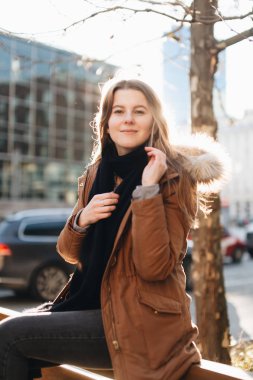 Genç güzel kız bankta oturup. Bir elinde onun eşarp asmak bir