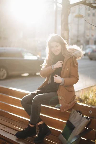 Молодая красивая девушка сидит на скамейке. Повесьте ее шарф в одной руке — стоковое фото