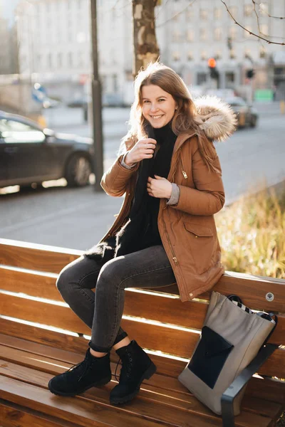 젊은 예쁜 여자는 벤치에 앉아. 한 손으로 그녀의 스카프를 걸어 한 — 스톡 사진