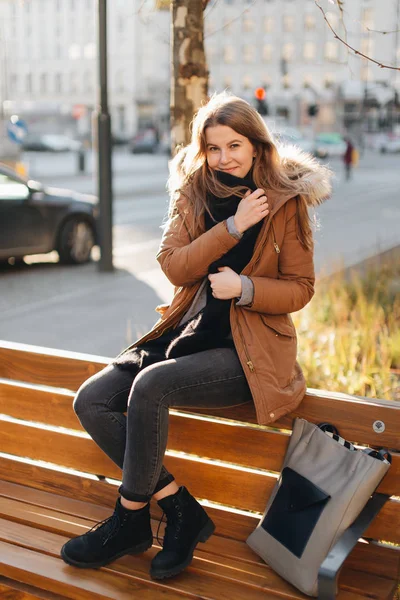 Ung vacker flicka sitter på bänken. Hänger hennes halsduk i ena handen en — Stockfoto