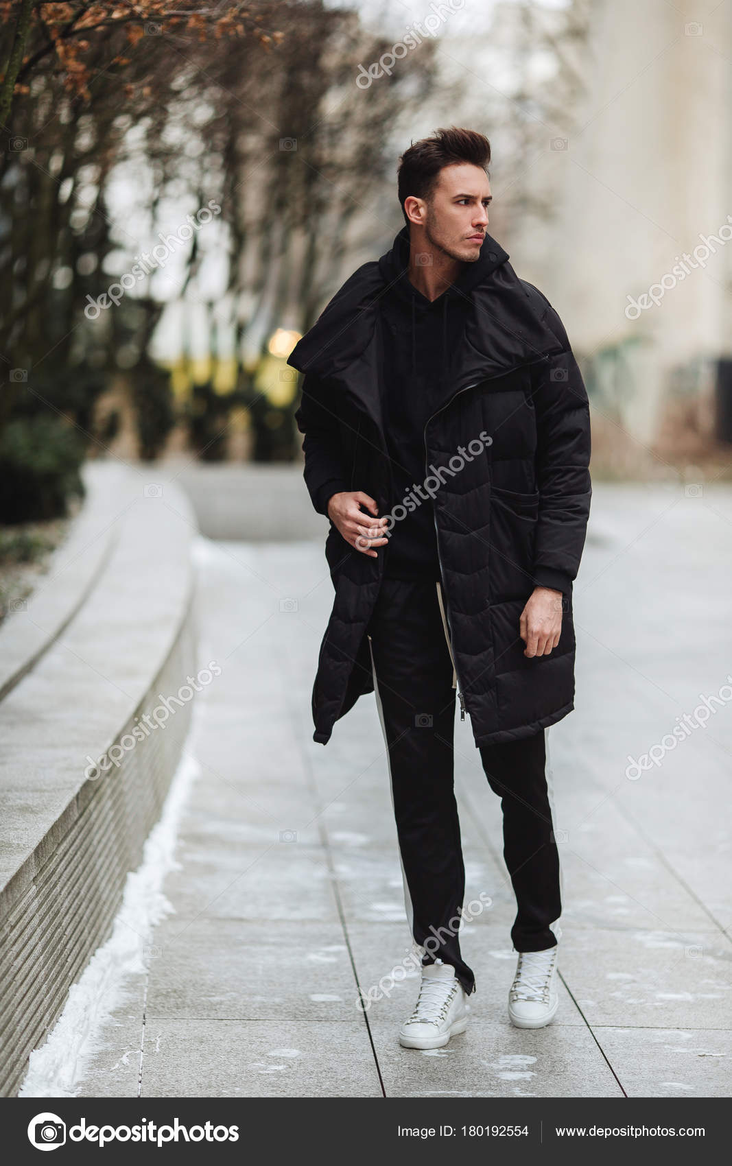 Hombre elegante wolk en la calle. El frío del invierno outfit. Gran  chaqueta con zapatillas blancas. Antecedentes Blured street. Foto modelo  profecional Fotografía de stock - Alamy