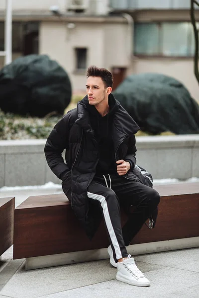 Traje moderno. Hombre de moda sentarse en el banco y mirar a su alrededor . —  Fotos de Stock