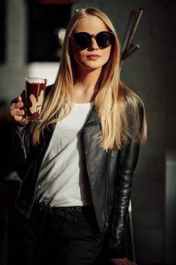 Güzel kız bir fincan lezzetli kahve ve waer gözlük tutun. Güneş