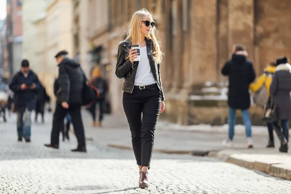 Genç güzel kız yürüyüş onun h üzerinde kahve ile sokakta