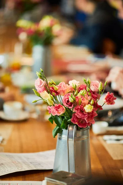 Table with flowers and people setting around