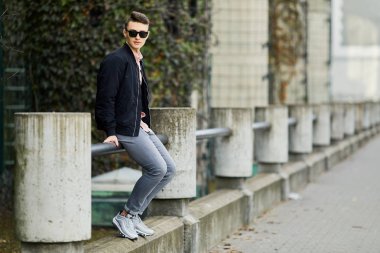 Bina, yakındaki bankta oturan genç adam giyim gözlük ve s