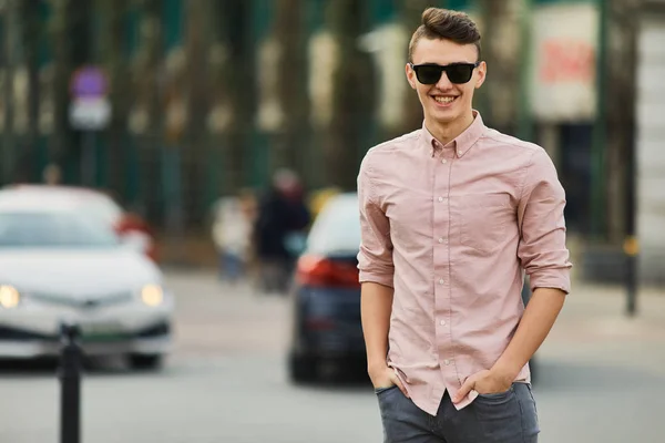 Молодий хлопчик, що йде по вулиці, носить окуляри і посміхається — стокове фото
