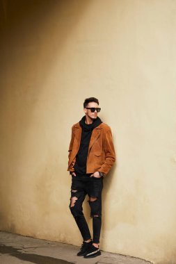 Model görünümlü bir adam duvara yakın dur ve onun gözlük savaşa tutun